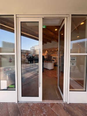 Glass doors with white wooden frame ahead. Push metal handles at center of doors to open.