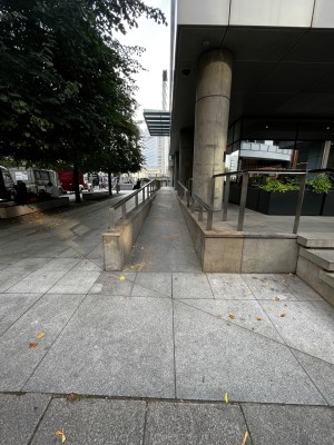From outside venue facing straight. Built-in ramp ahead. Metal handrails on both sides.