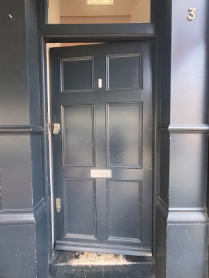 Black wooden door ahead. Push at center left to open.