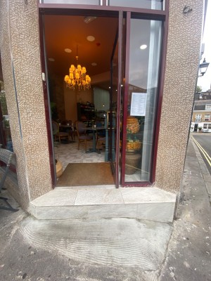 Glass door with dark red frame. Push from left to open. 1 step before doorway.