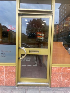 Glass door with yellow frame. Push silver handle on left to open.