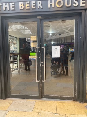 Glass doors with black frames ahead. Pull from metal handles in centre to open.