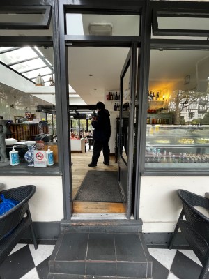 Glass door with grey frame. Push from left to open. One step up to door. Another step up through door. Small bump at foot of door.