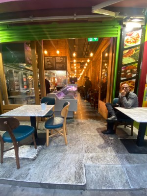 Built in ramp before door. Then glass door with wooden frame straight ahead. Push from left to open.