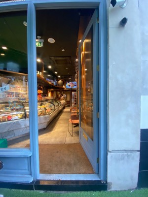 Glass door with light blue frame. Push from left to open.
