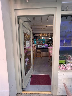 Glass door with green wooden frame ahead. Push metal handle on right to open.