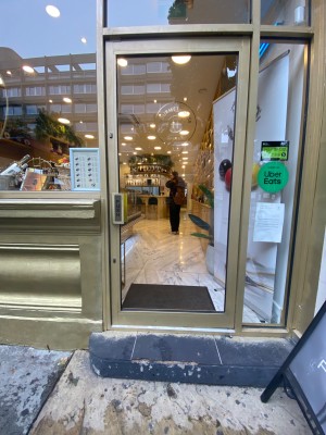 Glass door with frame painted gold. Push from left to open.