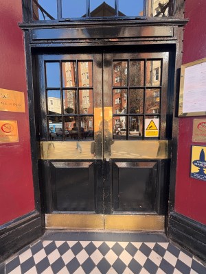 Double glass panel doors ahead. Push golden metal plaques at center of doors to open.