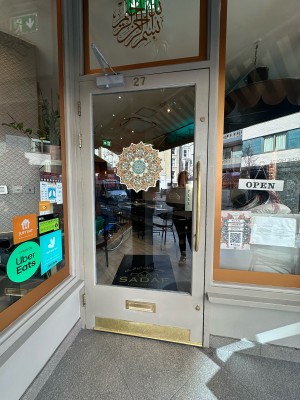 Glass door with green frame ahead. Pull from metal handle on right to open.