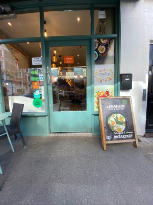 Glass door with green frame ahead. Push from metal handle on left to open.