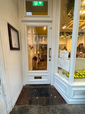 Glass door with wooden frame and a right side pull to open door. There is a small bump at the foot of door.