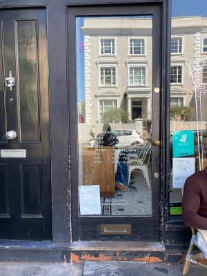 Glass door with black frame ahead. Push from metal handle on right to open.
