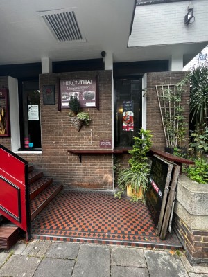 Facing storefront. One step up to landing. Staircase on left.