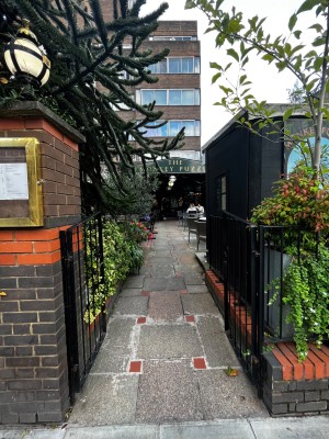 Push black iron gates from middle to open. Central path through outdoor front area leads to doors.
