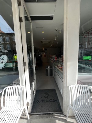 White framed glass door. Push silver handle on right to open. Door folds and slides over to left.