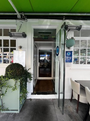 Step leading up to a glass door with white doorframe. Handle on left. Pull to open.