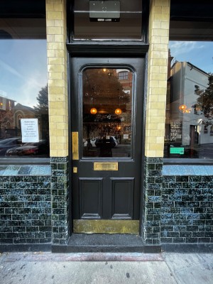 Glass door with black frame. One step up through door. Push from left to open.