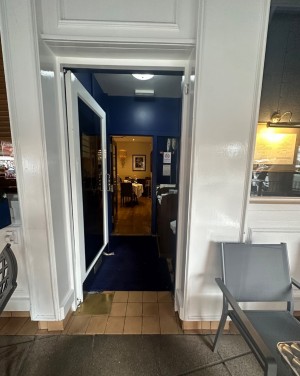 Glass door with white frame. Push silver handle on right to open