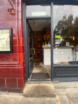 Glass door with black frame. Push from right to open.