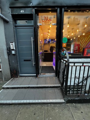 2 steps up to glass door. Push door from right to open. One further step through door.