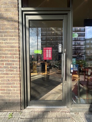 Glass door ahead with grey metal frame. Pull silver metal handle on right to open. Doorbell to right of door.