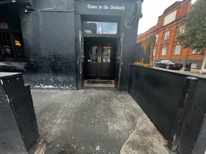 Path to door from street. Doors directly ahead past smoking area on left.