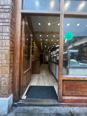 Glass door with wooden frame and metal handle on right. Push to open.