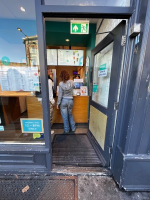 Glass door with grey frame. Push from left to open. One step through door.