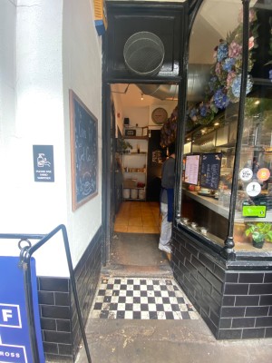 Opening ahead between glass wall on right and white wall on left. Glass door with black frame on back. Push to open via golden handle on right.