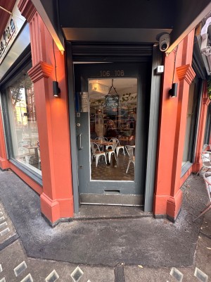 Grey wood and glass door in pink frame. Push metal handle on left to open.