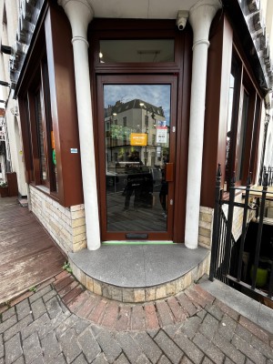 Glass door with brown frame. Push brown handle on right to open. One step up to entrance