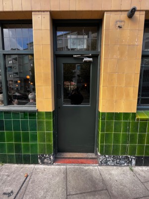 Green and glass panelled door. Push from right to open.