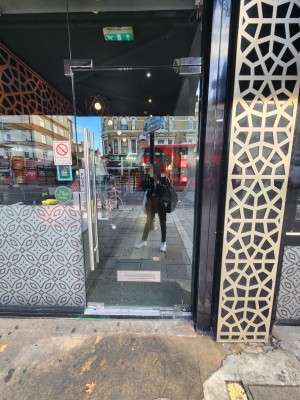 Very small step leading up to a glass door with silver handle. Push door open from the left.