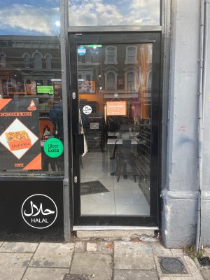 Glass door with black, metal frame. Push from left to open.