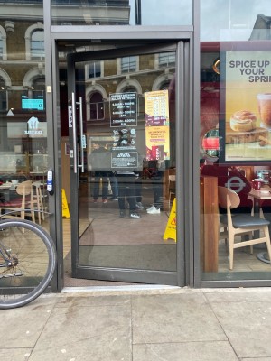 Glass door with green frame ahead. Push from metal handle on left to open.