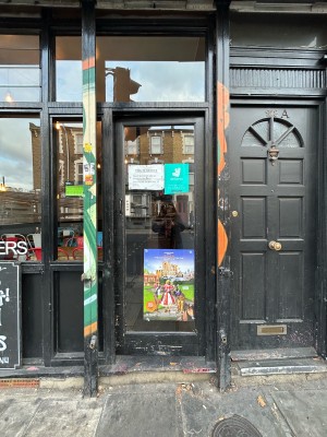 Black framed glass door with black handle on left. Push to open.