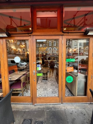 Glass door with wood frame and metal handle. Push from left to open.