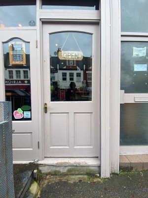 Glass door with white frame. Push from left to open.