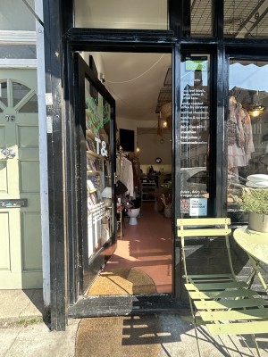 Glass door with black frame ahead. Push gold handle on right to open.