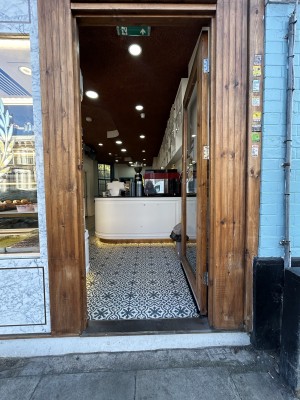 Glass door ahead with brown wooden frame. Push silver handle on left to open.