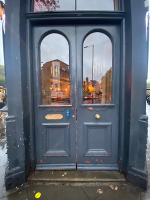 Glass doors with dark greg frames. Push from middle to open. 1 step before doorway. Doorbell for assistance to right of left door.