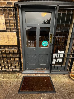 Glass door with grey frame. Push from right to open. One step up through door.