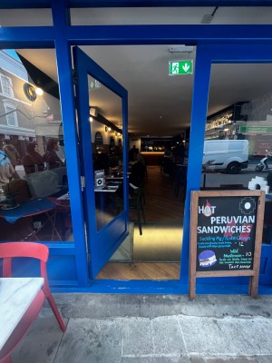 Glass door with blue frame. Push from right to open. Built in ramp up to door followed by small bump.