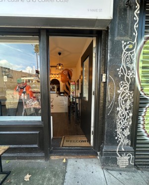 1 step followed by single wood and glass door with handle on the left. Push.
