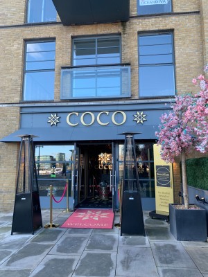 Photo of the main entrance. Double glass doors. First set of glass doors is open. Second glass door is single and shut, opens by pulling.