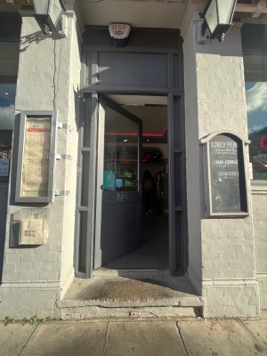 Glass paneled door with gray frame. Push sliver handle on right to open. Step up ahead of door.