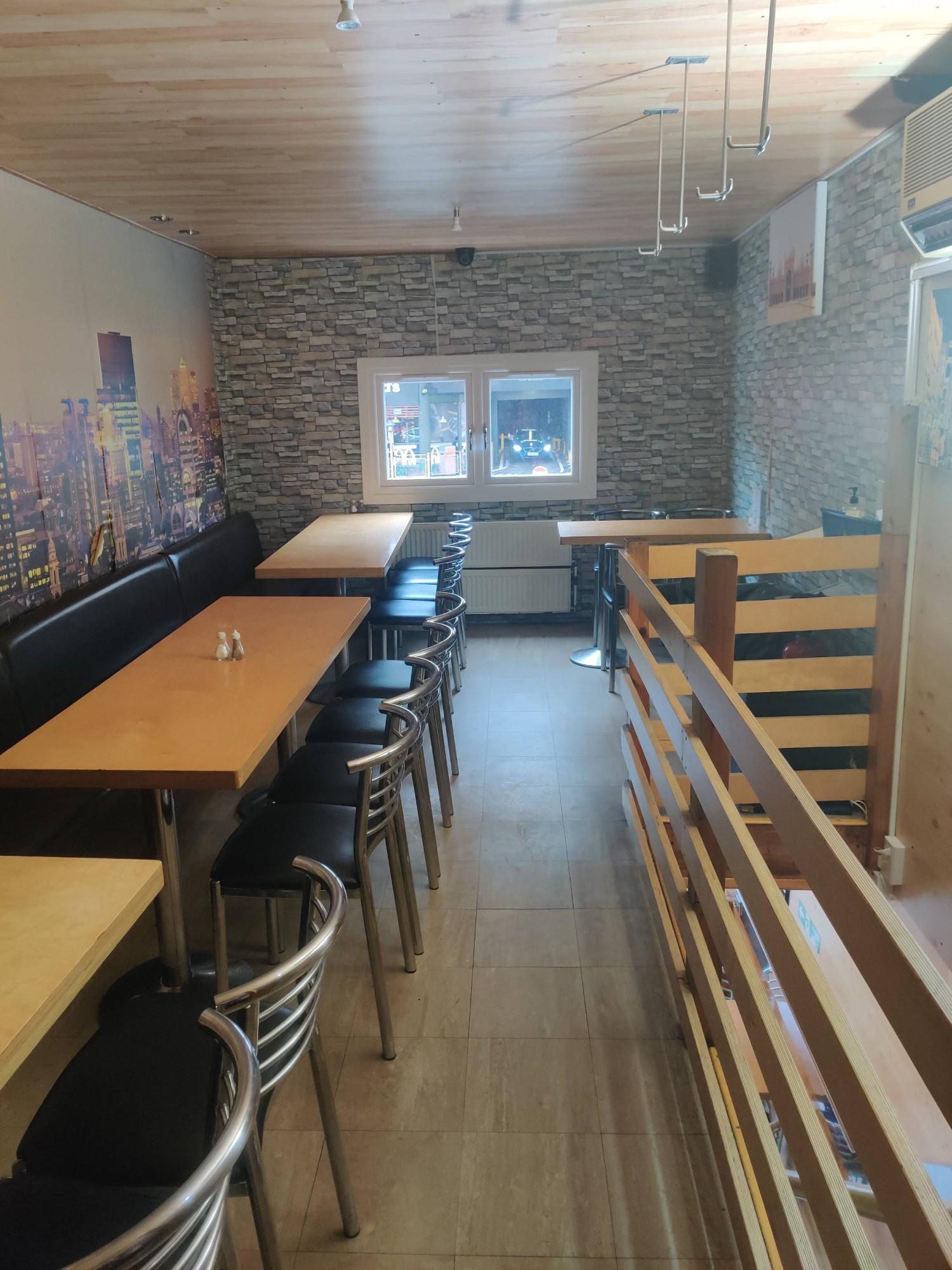 From top of stairs facing back. Half booth along left. Wooden railing on right.