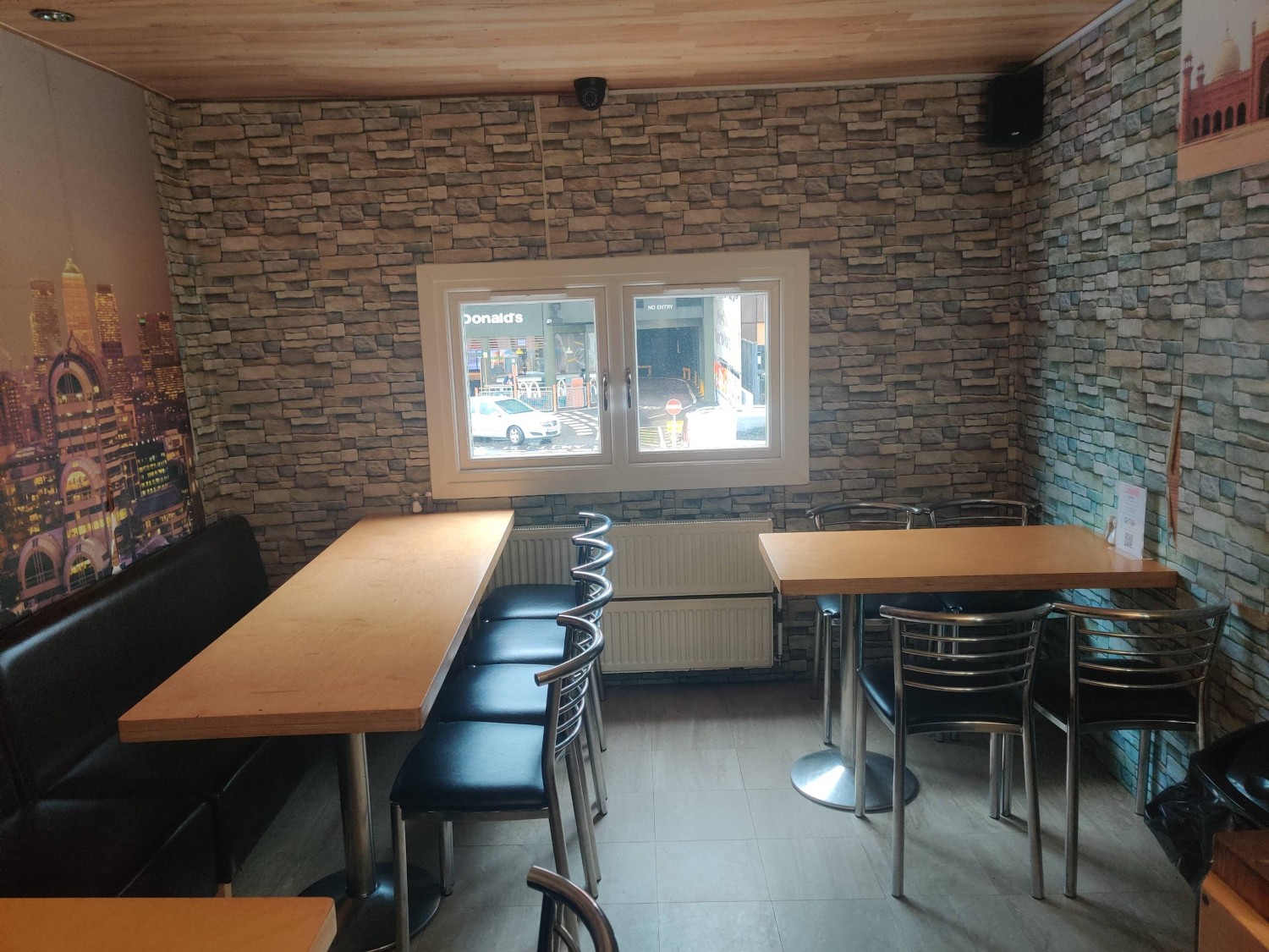 From end of wooden railing facing straight. Half booth on left. Table and chairs on right.