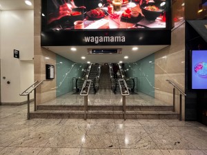 Form after Pho restaurant facing straight. Two steps up to escalators and stairs at back. Silver handrails on both sides of steps.