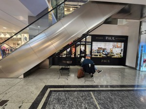 From mall hallway, looking straight at cafe. Tables and chairs ahead. Cafe counter to the right.